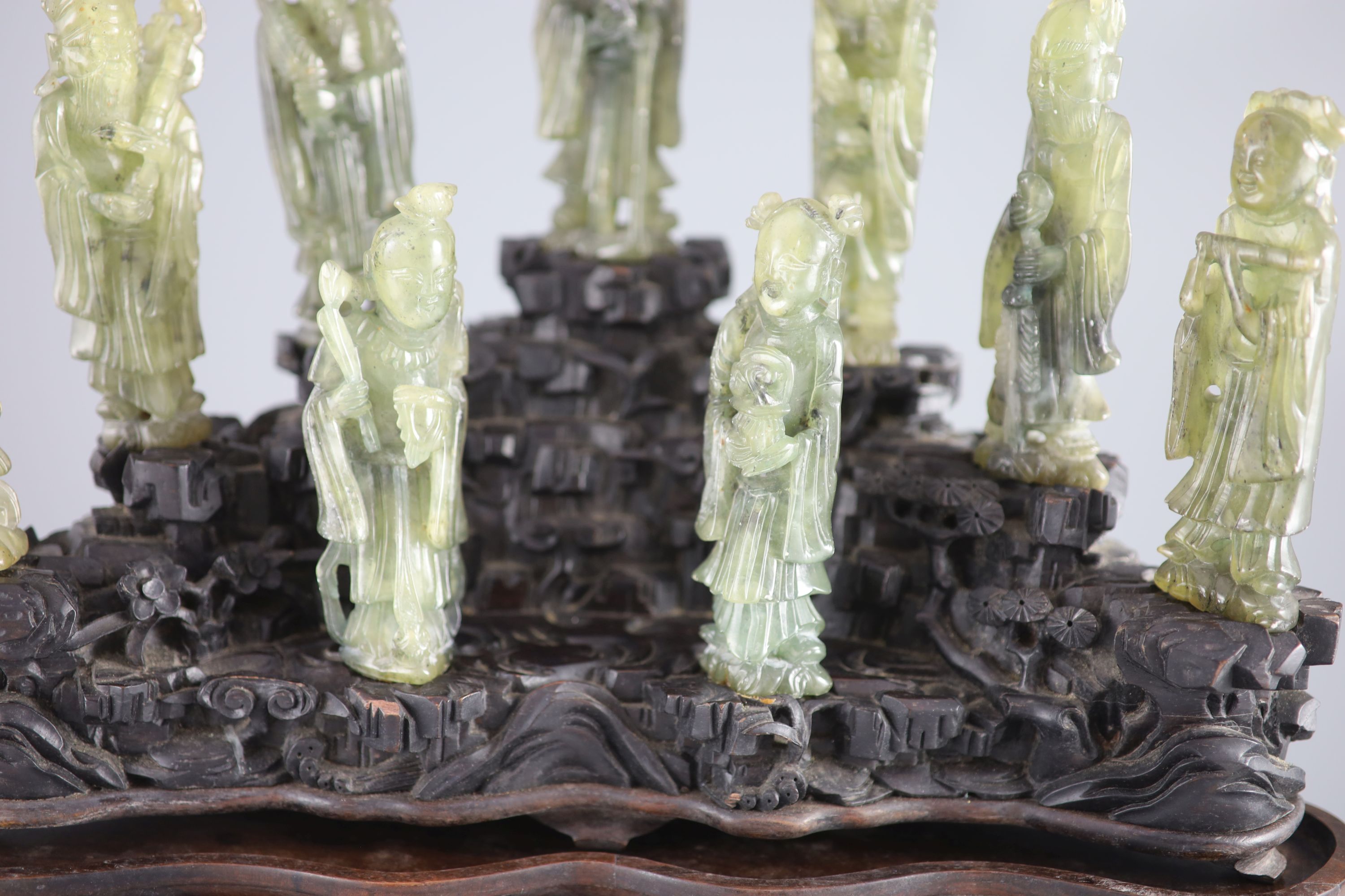 A set of nine Chinese soapstone figures of the Eight Immortals and Shou Lao, on a good zitan two piece rockwork stand, late Qing dyna